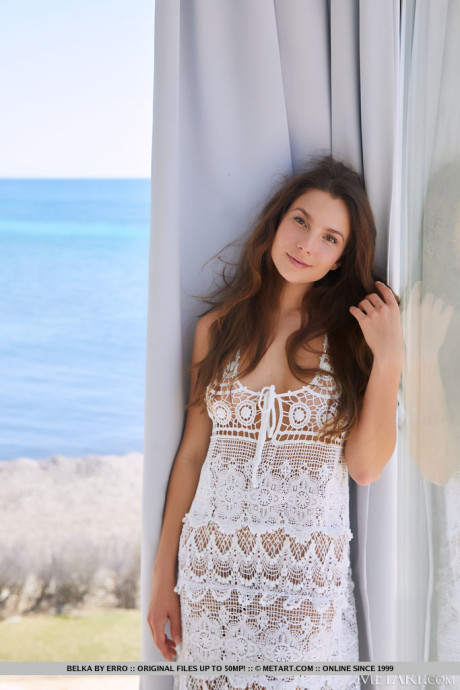 Beautiful model Belka invitingly tugs her crocheted see through dress which