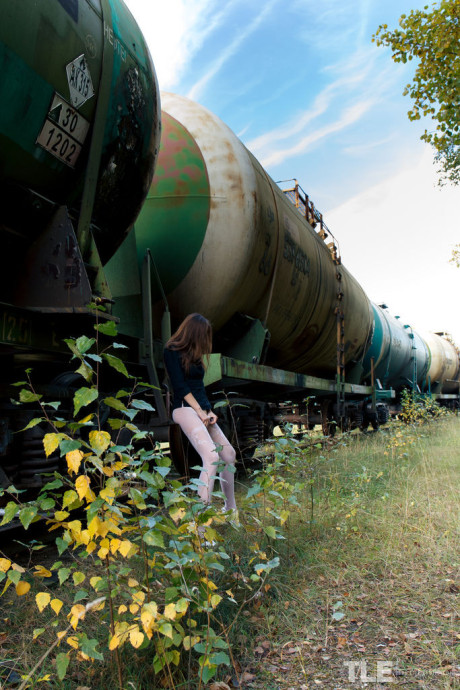 Thin teen Rebeka Ruby squats on a rail car before pissing on the tracks