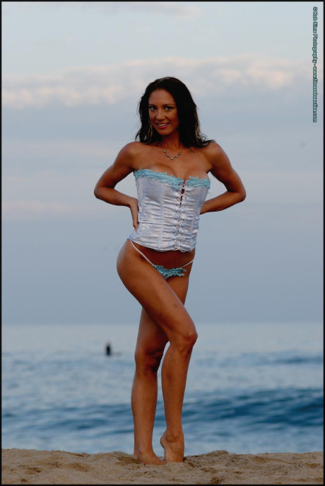 Fitness model Sarah Opal poses on a beach in a corset and a thong