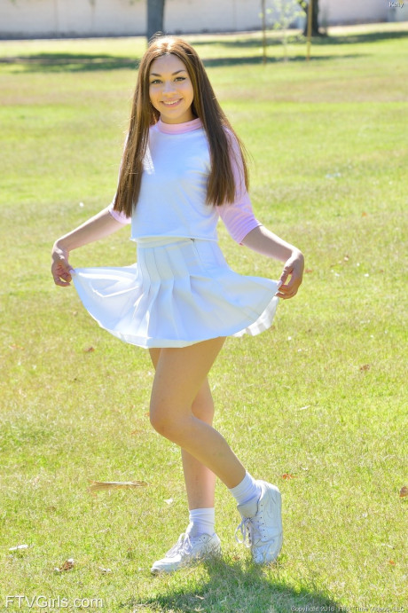 Brunette sweetie Kelly reveals her tiny tits and fingers her cunt in the park