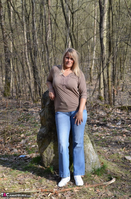 Middle-aged yellow-haired lovely Susi pulls down her jeans to show her bare behind