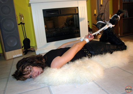 Clothed Caucasian female Jenna struggles on a rug while hogtied