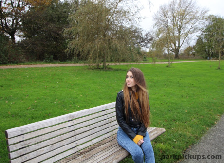 Long-haired teenie in a leather jacket puts a hard penis in her mouth in a park