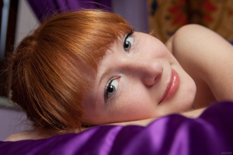 Curly-haired young Rochelle A presents her nice titties and trimmed redhead snatch