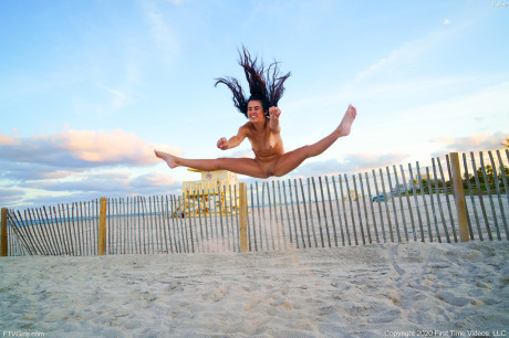 Attractive brunette Kylie displays her athletic ability in the naked on a sandy beach