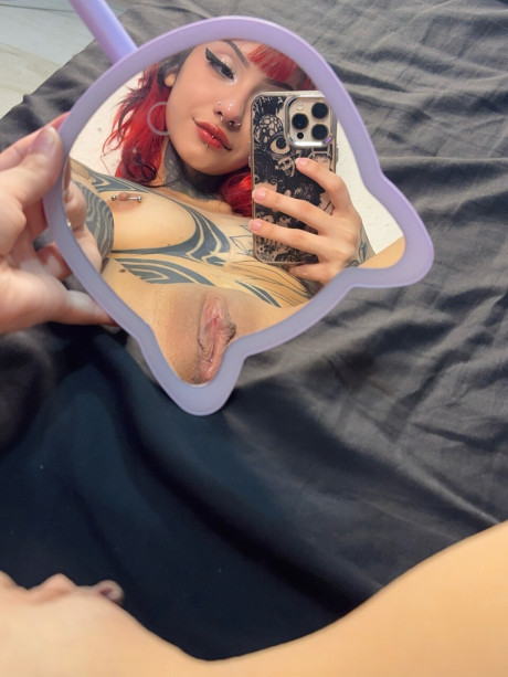 Tattooed redhead takes selfies while getting undressed in her bedroom