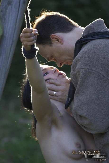 Naked brunette Ally Style is roasted over a fire during BDSM training