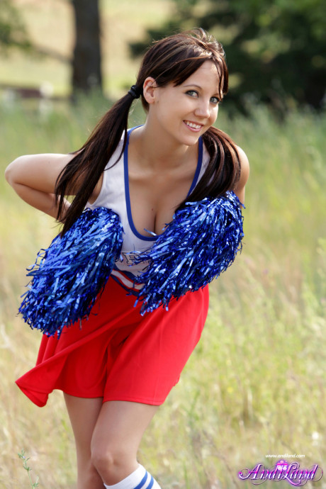 Teen cheerleader Andi Land exposes her titties and pussy while in a field