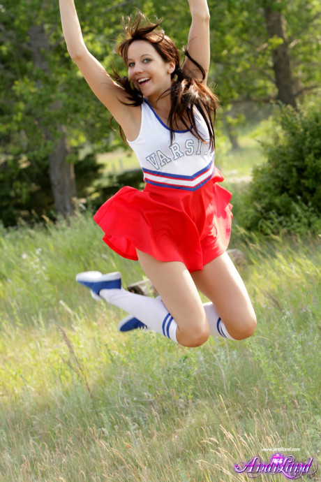Teen cheerleader Andi Land exposes her titties and pussy while in a field