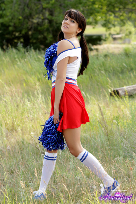 Teen cheerleader Andi Land exposes her titties and pussy while in a field