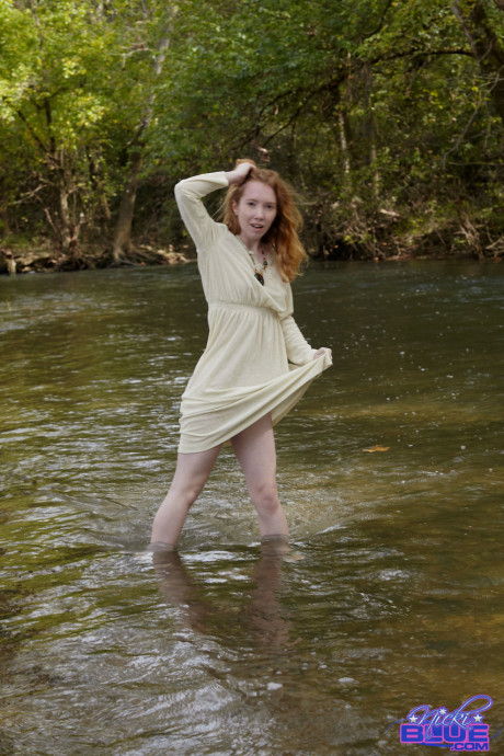Redheaded American pornstar Nicki Blue reveals her sexy behind in the river