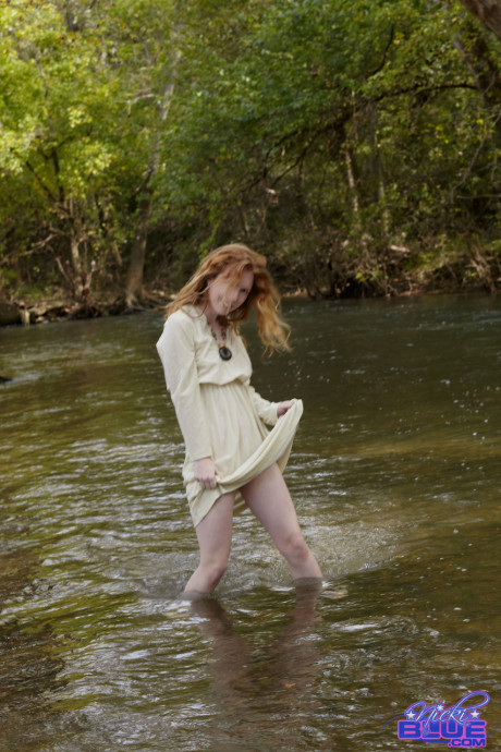 Redheaded American pornstar Nicki Blue reveals her sexy behind in the river