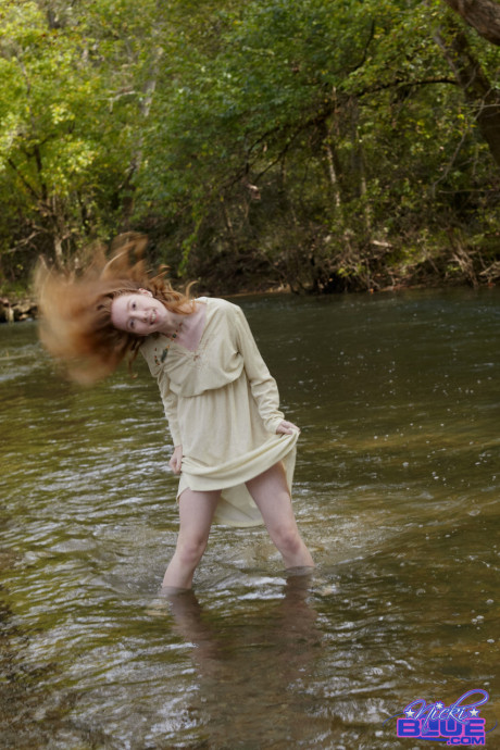 Redheaded American pornstar Nicki Blue reveals her sexy behind in the river