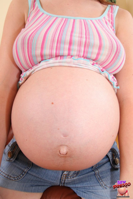 Pregnant amateur strips to her socks on a couch in a confident manner