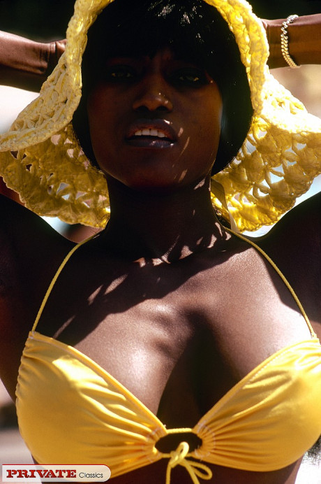 Black female in sunhat and bikini heads into the bushes to pose nude