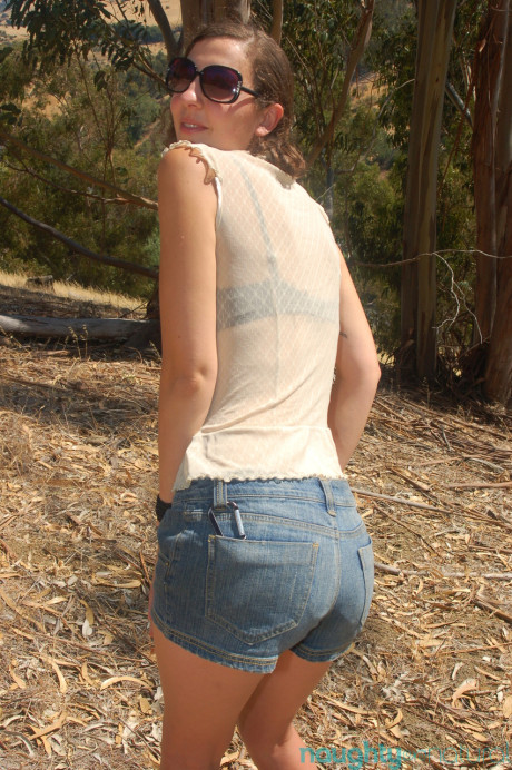 Brunette amateur Artemis shows her tiny titties and rubs her bush outdoors