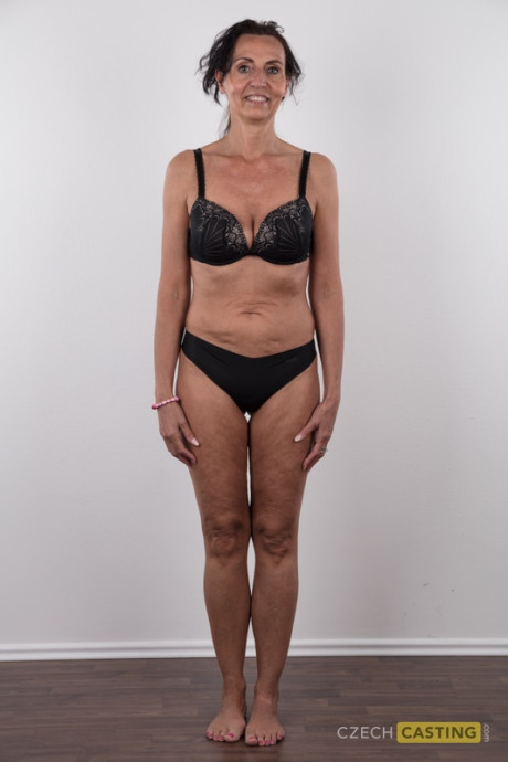 Cougar girl Klaudie stands undressed after removing her clothing in solo action