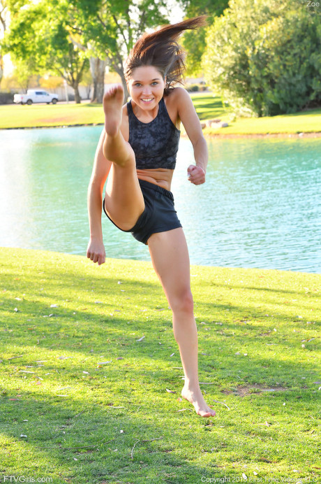 Teenage beauty in charming outfit Zoe doing exercise outdoors by the water