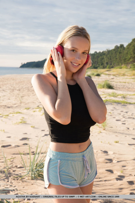 Young young blondie with great melons showcases her smooth vagina on the beach