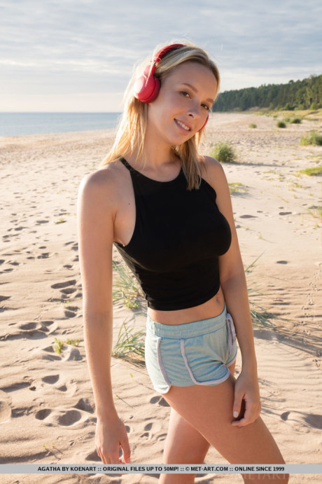 Young young blondie with great melons showcases her smooth vagina on the beach