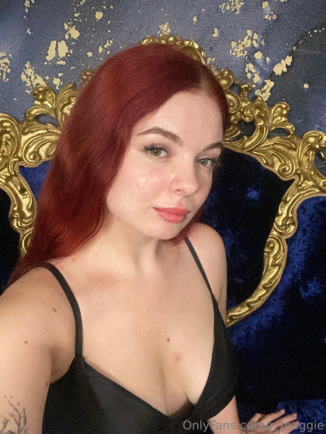 Cute red hair holds the handle of a giant dildo while remaining clothed
