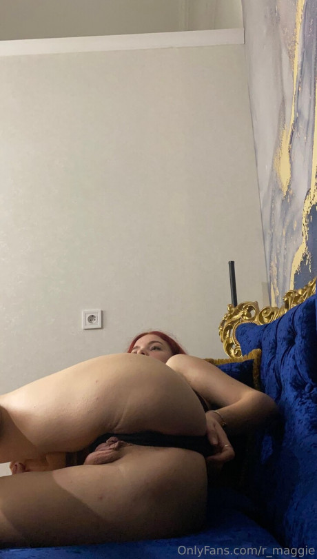 Cute red hair holds the handle of a giant dildo while remaining clothed