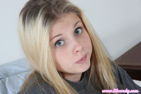 Yellow-haired babe Lil Candy spreads her vagina lips up close in a bedroom solo