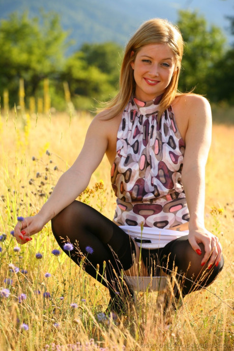 Pretty amateur teenie Nikki F squats as she poses in thong panties in the field