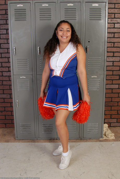 Petite curly haired cheerleader Reena shows her thick booty and bushy pussy