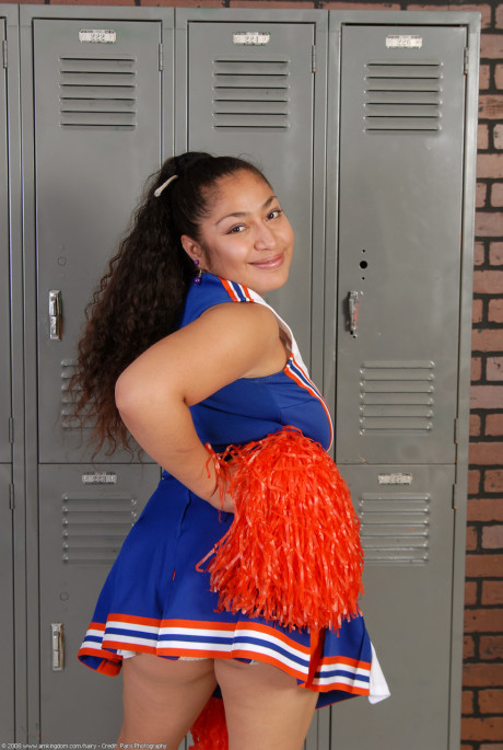 Petite curly haired cheerleader Reena shows her thick booty and bushy pussy