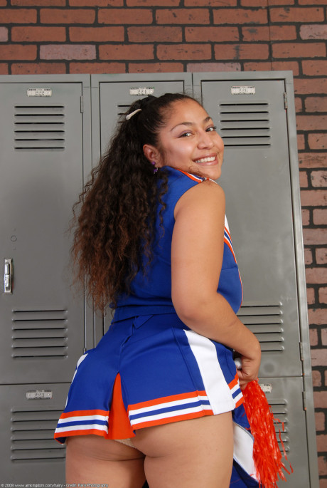 Petite curly haired cheerleader Reena shows her thick booty and bushy pussy