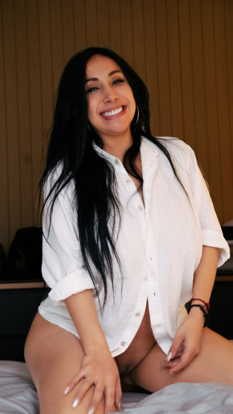 Curvy brunette Sandra Sierrra exposes her massive breasts while kneeling on a bed