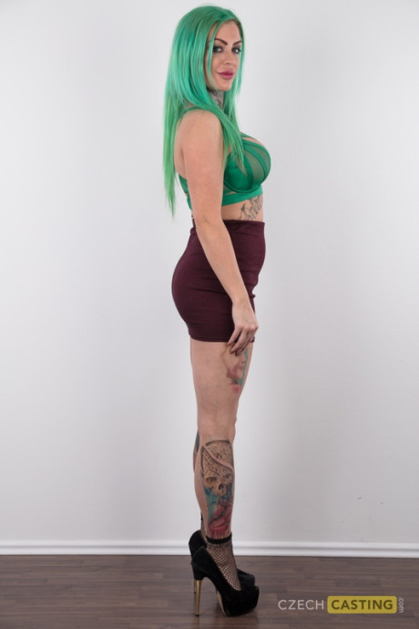 Tattooed girl gf girl with green hair and pierced nipples stands undressed after disrobing